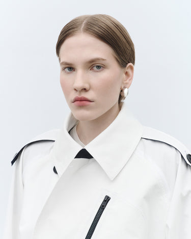 White cropped trench jacket with pointed collar and black chest strap detail