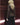 Dark gray cardigan back with blue button placket glimpsed and ribbed cuffs, tied waist belt