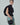 Side view of black tuxedo vest shirt with sculptural cap sleeves and a long waist tie