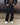 Black track pants with elastic waistband, side pockets, and relaxed tapered legs