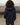 Dark wind shell jacket with attached hood, back view, zippered front