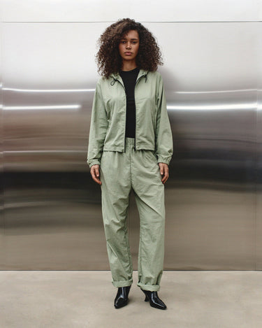 Light green track pants with elastic waistband, relaxed straight legs, cuffed hems
