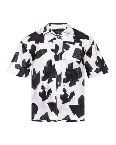 Camp shirt close-up: button-front collar, black abstract print on white; THEO label.