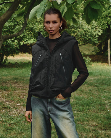 Black hooded vest on model with full-zip front and side zip pockets