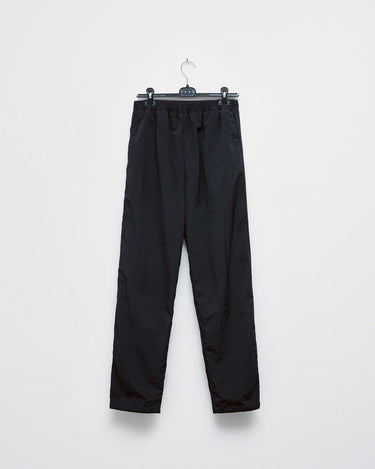 Black track pants with elastic waistband and tapered legs, hanging on a hanger