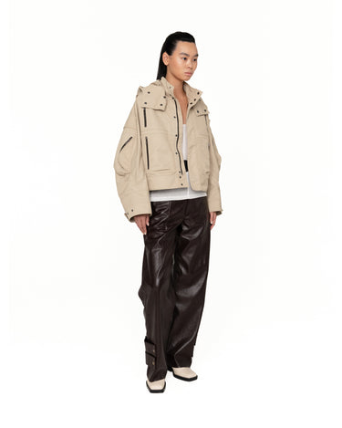 Beige hooded jacket with vertical chest pockets, flap sleeve details, and snap front