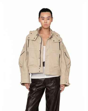 Beige hooded jacket close-up with flap chest pockets, snap front placket, and studded buttons