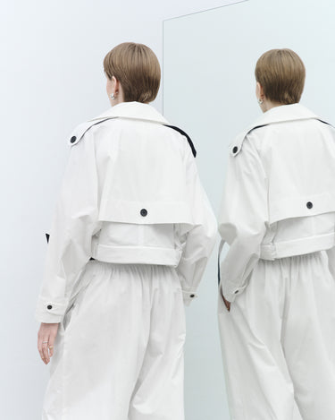 White cropped trench jacket back view with shoulder tabs and black strap details
