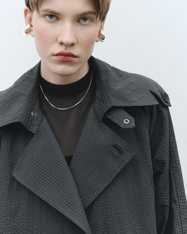 Textured trench coat close-up, wide lapels, buttoned shoulder strap detail