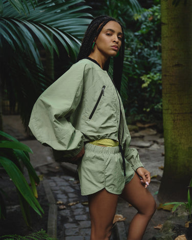 Light green bomber jacket with black-trimmed collar, front zipper, and zip pocket details