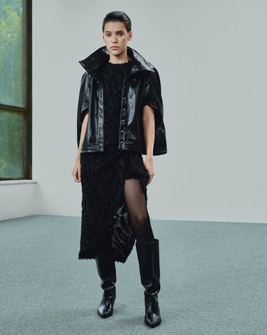 Black cropped eco-leather cape with draped shoulders and front snap buttons