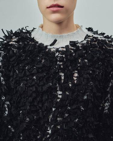 Black shredded sweater close-up with crew neckline and ragged texture