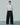 Black fringed wide-leg trousers shown with hands in side pockets.