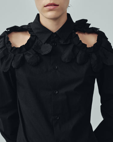 Close-up of black button-up shirt with petal ruffle shoulder details and pointed collar