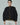 Textured black draped sweater with olive sleeves and hem, shown from the front