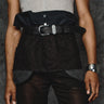 Black apron detail view: top flap with snap buttons and front belt with metal buckle