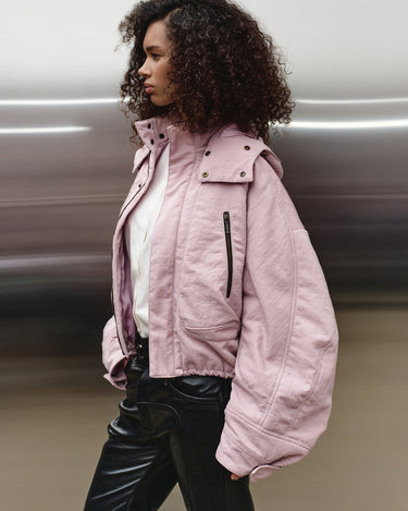 Pink hooded nylon jacket with front zipper and vertical pocket zips, side view