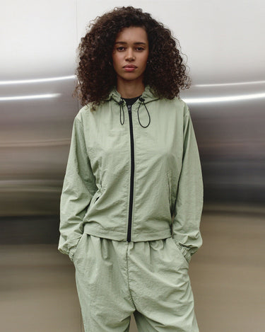 Light green hooded wind shell jacket with drawstring neckline and black zipper