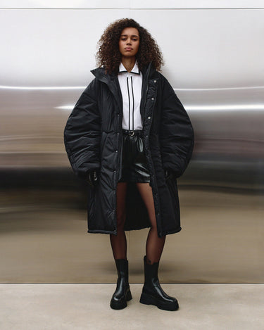 Black hooded puffer coat over white top, with snap buttons and drawstring waist belt