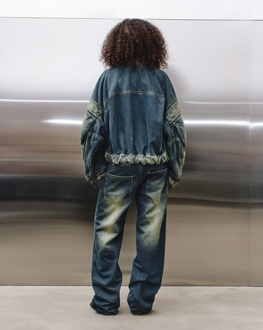 Back view of faded blue denim jacket with hood, elastic hem, and seam stitching