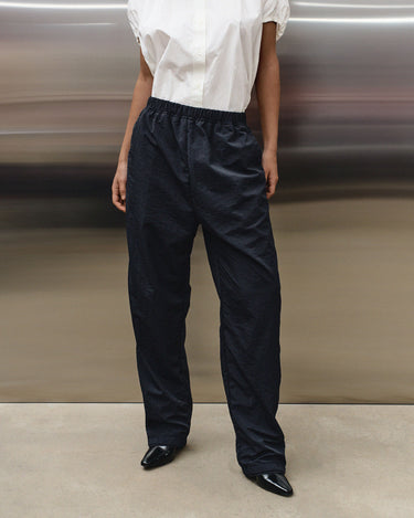 Black track pants with elastic waistband and relaxed legs, front view