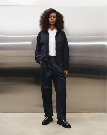 Black track pants with relaxed leg and elastic cuffs, worn with boots