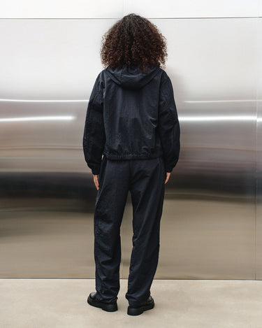 Black track pants with elastic waistband and full-length relaxed fit, back view