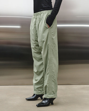Light green track pants from the side, elastic waistband and cuffed ankle hems