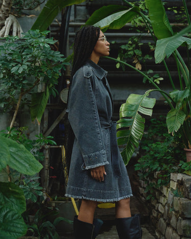 Gray denim trench coat side view with buttoned placket and cuffed sleeves