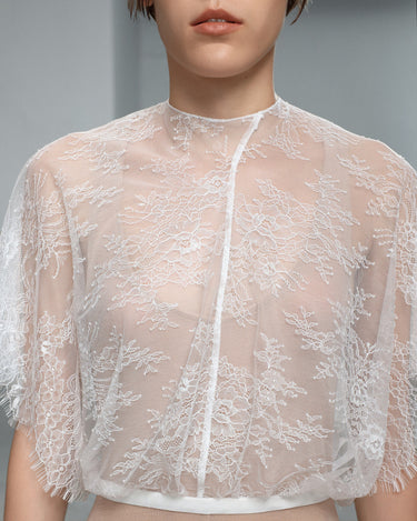 White lace blouse close-up with scalloped floral embroidery and button front