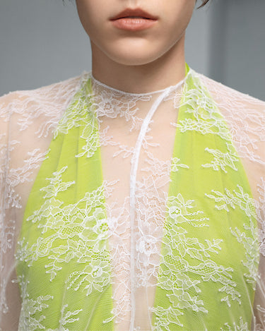 White lace dress neckline detail with neon-lime floral embroidery and tie keyhole