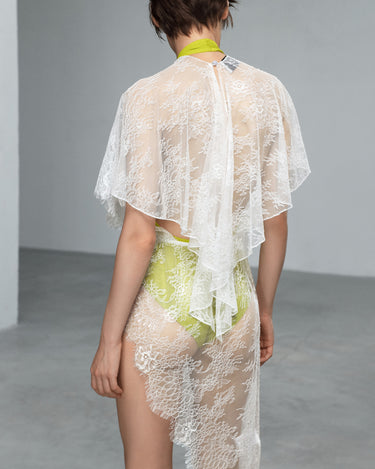 Back view of white lace dress with cape sleeves and neon-lime embroidered panel