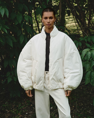 Cream padded bomber jacket worn front, stand collar and zipper with two chest pockets