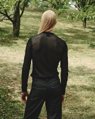 Dark sheer mesh turtleneck top, back view with long sleeves and fitted cuffs