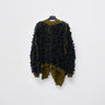 Back of men's textured sweater, with dark layered fabric, khaki knit trim and asymmetrical draped hem