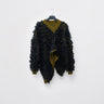 Front view of a textured black draped sweater with an olive V-neck and uneven hem